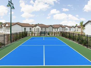 A tennis court in front of a row of houses  at The Hadley - North Port, FL Apartments, North Port 34287